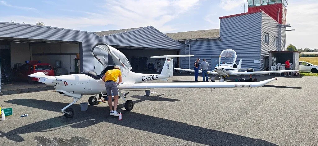Helfer putzt die geöffnete Kabine der D-ERLE, im Hintergrund weitere Maschine und Hangar